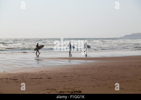 Les surfeurs en marchant le long du bord de l'eau à Lunan Bay Banque D'Images