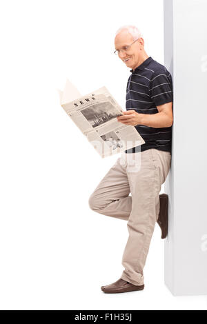 De toute la longueur un haut représentant de lire le journal et appuyé contre un mur isolé sur fond blanc Banque D'Images