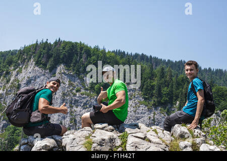 Heureux randonneurs masculins assise sur le bord d'une très haute falaise Banque D'Images