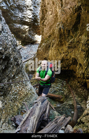 Caucasian hiker grimper sur une des chaînes de sécurité à travers un canyon très difficile Banque D'Images