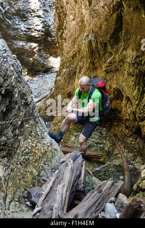 Caucasian hiker grimper sur une des chaînes de sécurité à travers un canyon très difficile Banque D'Images