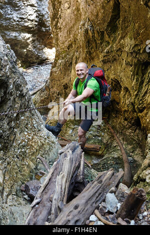 Caucasian hiker grimper sur une des chaînes de sécurité à travers un canyon très difficile Banque D'Images