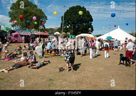 Les familles se réunissent autour de stands de nourriture et de tentes de l'événement dans le soleil d'été au Port Eliot Cornwall Festival Banque D'Images