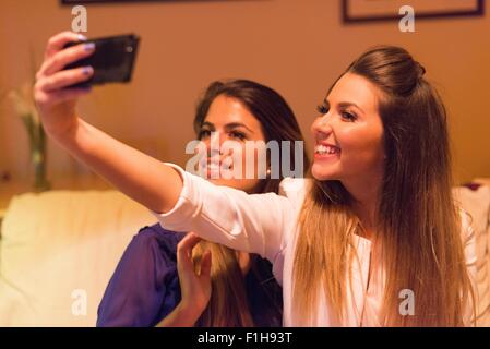 Deux jeunes femmes, taking self portrait à l'aide de smartphone Banque D'Images