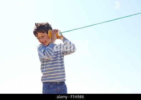Jeune garçon, holding cup et de chaîne à l'autre téléphone Banque D'Images