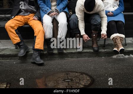 Ami assis sur un banc, l'homme attachant lacets Banque D'Images