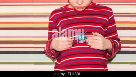 Little girl holding a toy plastique araignée dans ses mains. Image conceptuelle de l'enfance, la curiosité, la fantaisie et l'aventure. Banque D'Images