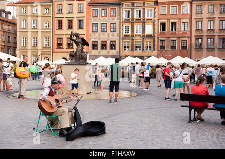 Vieil homme musicien ambulant qui joue de la guitare en concert Place du marché de la vieille ville square à Varsovie, Pologne. Street art artiste chanteur seul spectacle. Banque D'Images