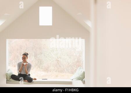 Mid adult woman sitting in window seat Banque D'Images