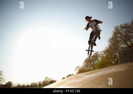 Jeune homme, au milieu de l'air, faisant stunt bmx sur at skatepark Banque D'Images