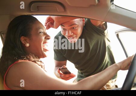 Jeune homme debout à ouvrir la porte de voiture à young woman smiling Banque D'Images