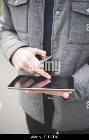 Portrait de mains de jeune businessman using digital tablet et téléphone mobile. Banque D'Images