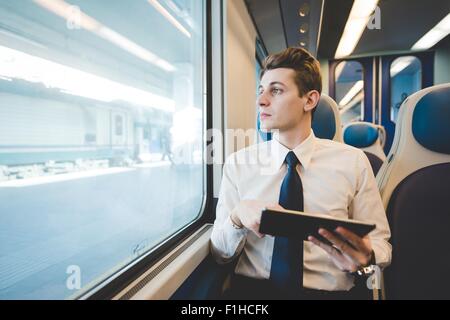 Portrait of young businessman using digital tablet de banlieue sur le train. Banque D'Images