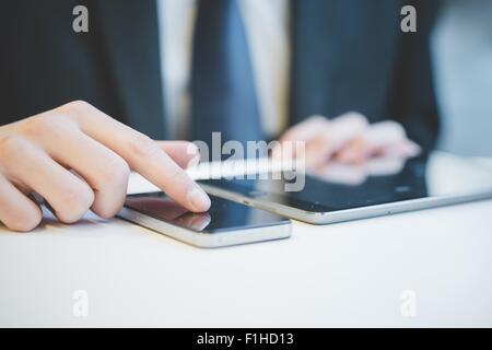 Portrait de mains de jeune businessman using digital tablet et téléphone mobile. Banque D'Images