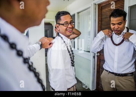 Trois jeunes hommes se préparer à porter de mariage hawaïen perles kukui nut, Kaaawa, Oahu, Hawaii, USA Banque D'Images