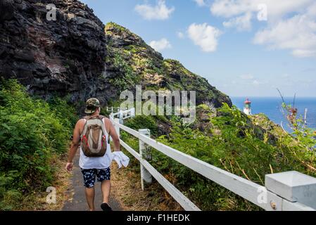 Vue arrière du jeune homme marchant vers touristiques Makapuu phare, Oahu, Hawaii, USA Banque D'Images