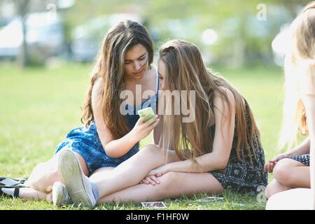 Deux adolescentes smartphone lecture textes dans park Banque D'Images