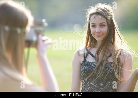 Teenage girl photographing meilleur ami à l'aide de la caméra dans park Banque D'Images