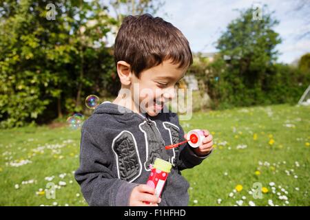 Portrait of boy blowing bubbles in garden Banque D'Images