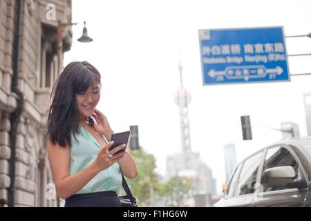 Young businesswoman, à l'aide de l'extérieur, smartphone, Shanghai, Chine Banque D'Images