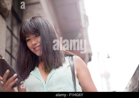 Young businesswoman, à l'aide de l'extérieur, smartphone, Shanghai, Chine Banque D'Images