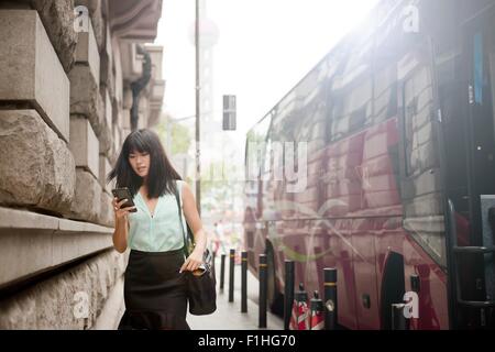 Young businesswoman, à l'aide de l'extérieur, smartphone, Shanghai, Chine Banque D'Images