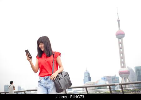 Young businesswoman, à l'aide de l'extérieur, smartphone, Shanghai, Chine Banque D'Images