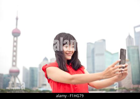 Young woman looking at smartphone, à l'extérieur, Shanghai, Chine Banque D'Images