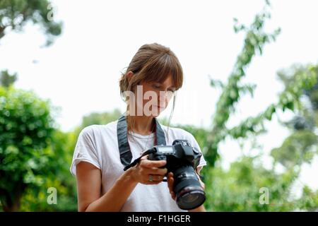 Mid adult woman looking at digital camera Banque D'Images