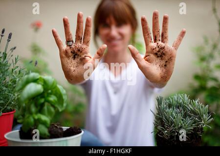 Mid adult woman holding sol couvert hands up Banque D'Images