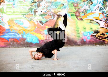 Jeune femme à l'envers contre les graffitis gel breakdance Banque D'Images