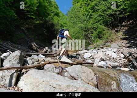 Young male hiker crossing river Banque D'Images