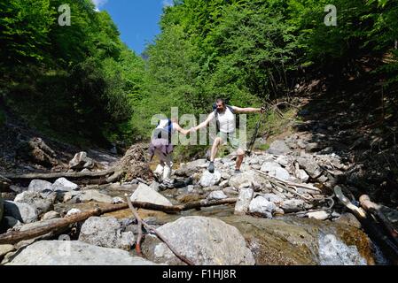 Deux randonneurs mature crossing river Banque D'Images