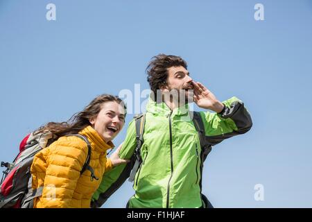 Couple de randonnée contre le ciel bleu de rire et crier Banque D'Images