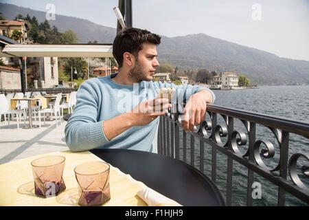 Jeune homme à la recherche de restaurant au bord du lac, lac Mergozzo, Verbania, Piemonte, Italie Banque D'Images