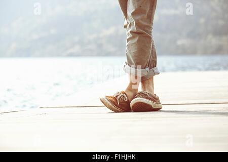 Pieds de jeune homme debout sur la jetée, lac Mergozzo, Verbania, Piemonte, Italie Banque D'Images