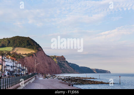 Voir l'est sur une soirée d'été le long du front de mer à Sidmouth avec les falaises rouges à l'arrière-plan. Banque D'Images