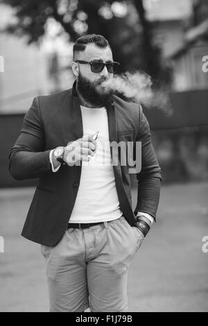 Homme avec une barbe fume cigarette électronique Banque D'Images