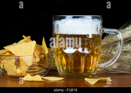 Pinte de bière et des chips avec du blé sur fond noir. Banque D'Images