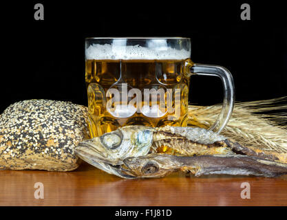 Pinte de bière avec du pain, du maquereau et de blé sur fond noir. Banque D'Images