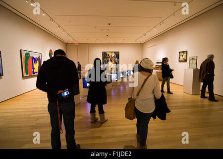 Diverses personnes dans une galerie d'art avec visualisation MoMA une installation de téléviseurs sur le sol et les peintures sur les murs Banque D'Images