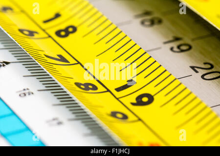 Les règles. Rouleau en acier bande jaune règle montrant 18-19 pouces au-dessus des autres dirigeants. Close up. Banque D'Images