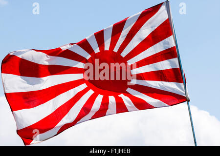 Drapeau japonais voletant dans le vent. La seconde guerre mondiale, version soleil levant, Jyurokujo Kyokujitsu-ki, contre fond de ciel bleu. Banque D'Images