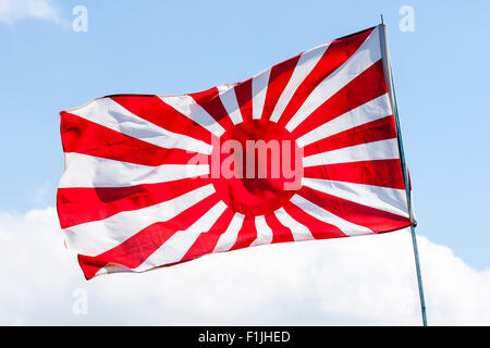 Drapeau japonais voletant dans le vent. La seconde guerre mondiale, version soleil levant, Jyurokujo Kyokujitsu-ki, contre fond de ciel bleu. Banque D'Images