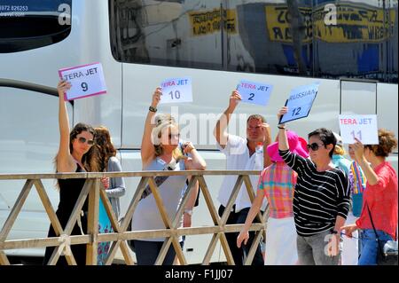 Excursion guidée reps holding up tour numéros voyage pour les passagers, lorsqu'ils arrivent dans le port de Santorin d''Ormos Athinios Banque D'Images