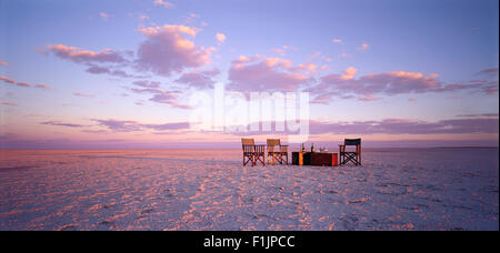 Table et chaises dans le désert au coucher du soleil Kubu Island, Botswana, Africa Banque D'Images