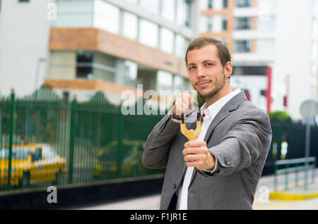 Bel homme d'affaires visant un concentré au fond de la ville urbaine de slingshot Banque D'Images