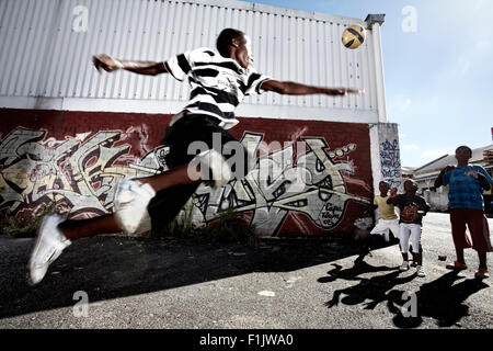 Garçons jouant au football dans la rue Banque D'Images
