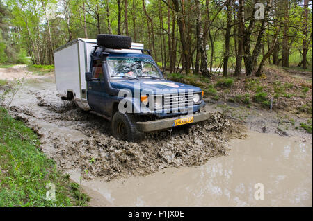 Une Toyota est la conduite dans un étang d'eau sur un terrain hors de la route et les véhicules de land cruisers Banque D'Images