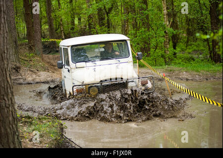 Une jeep est la conduite dans un étang d'eau sur un terrain de la route de land cruisers Banque D'Images